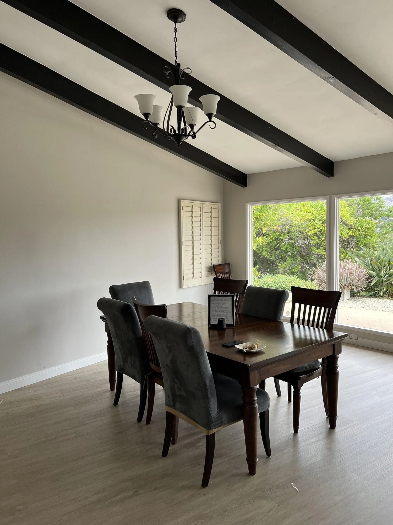 Clubhouse dining room: a wood table with six chairs under a beamed ceiling, beside windows onto the garden