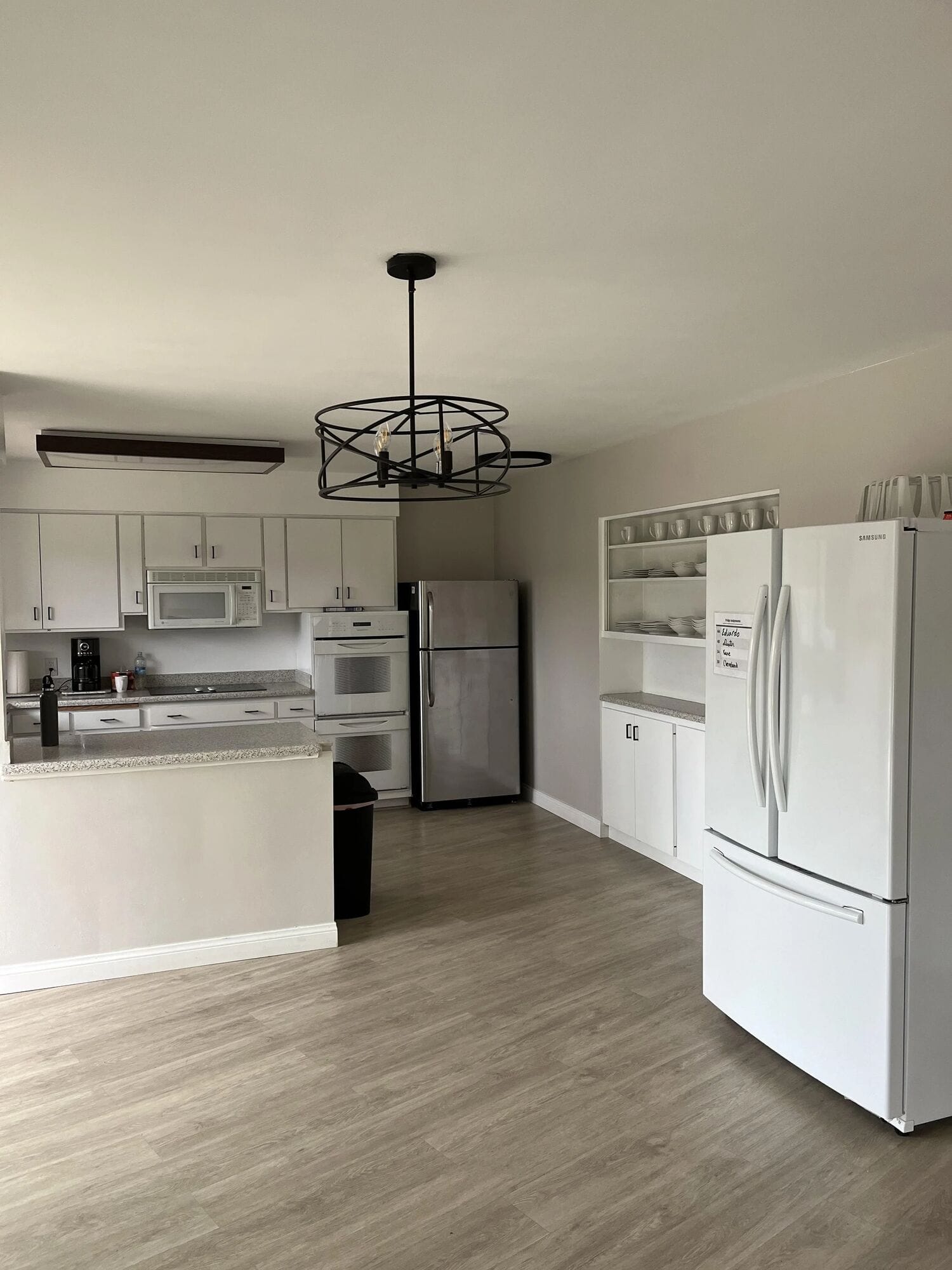 Clubhouse kitchen with white cabinets, a double wall oven and two refrigerators