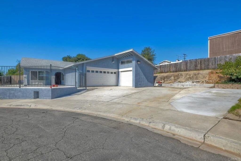 The Poolhouse: a single-story gray home with a two-car garage at the end of a quiet San Marcos street