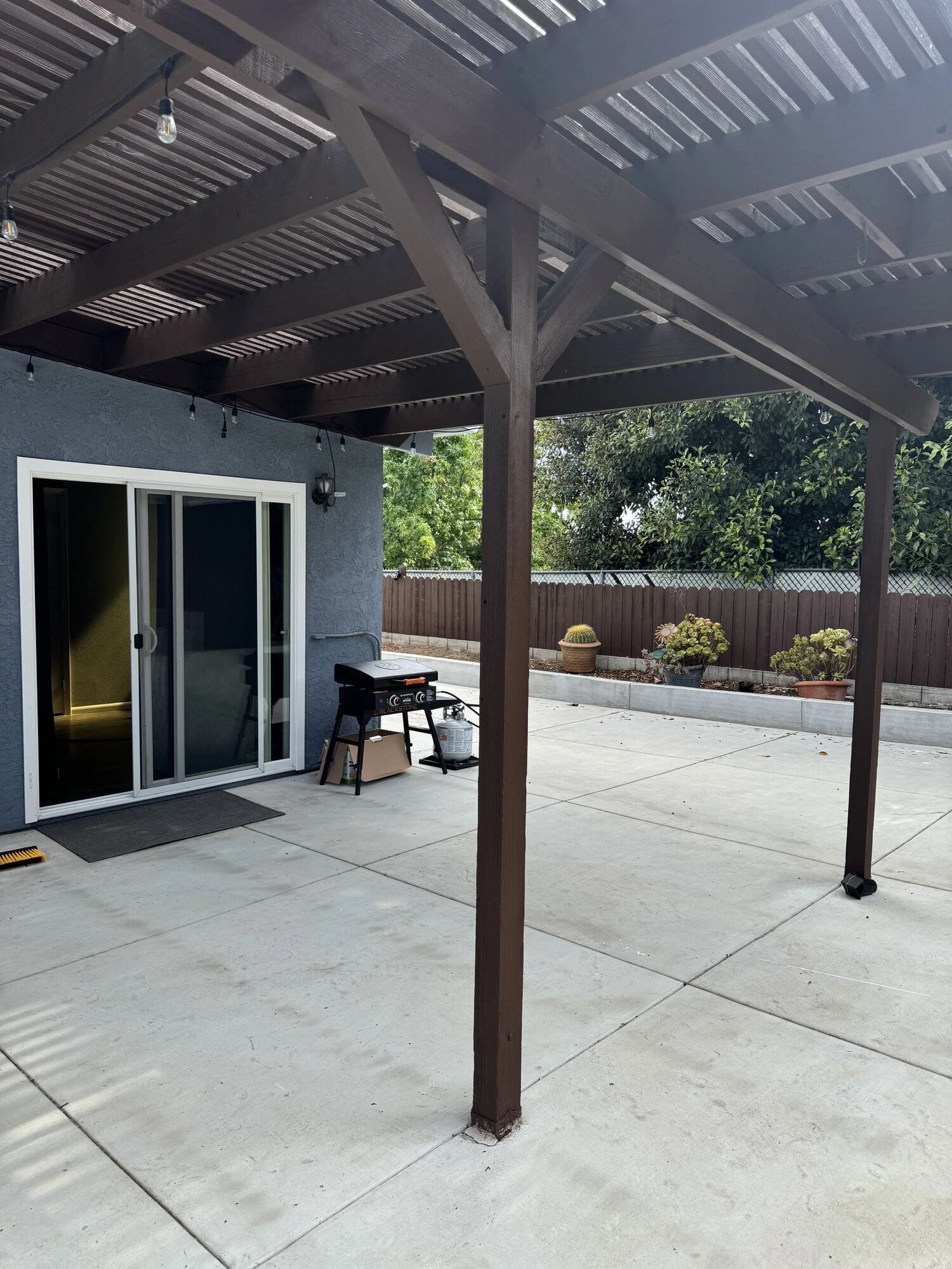 The Poolhouse covered patio with a wood pergola, sliding doors and a small table