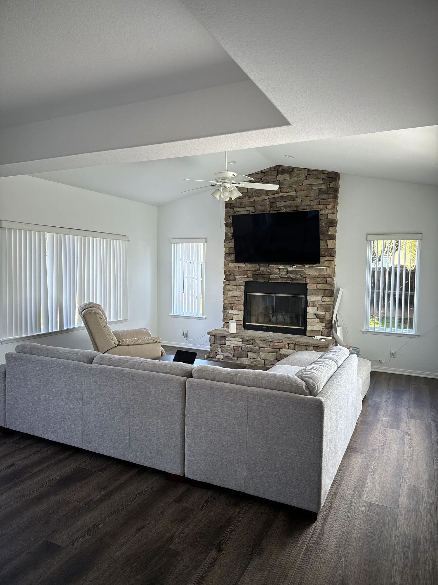 Skyhouse living room with a large white sectional and a stacked-stone fireplace with a TV above