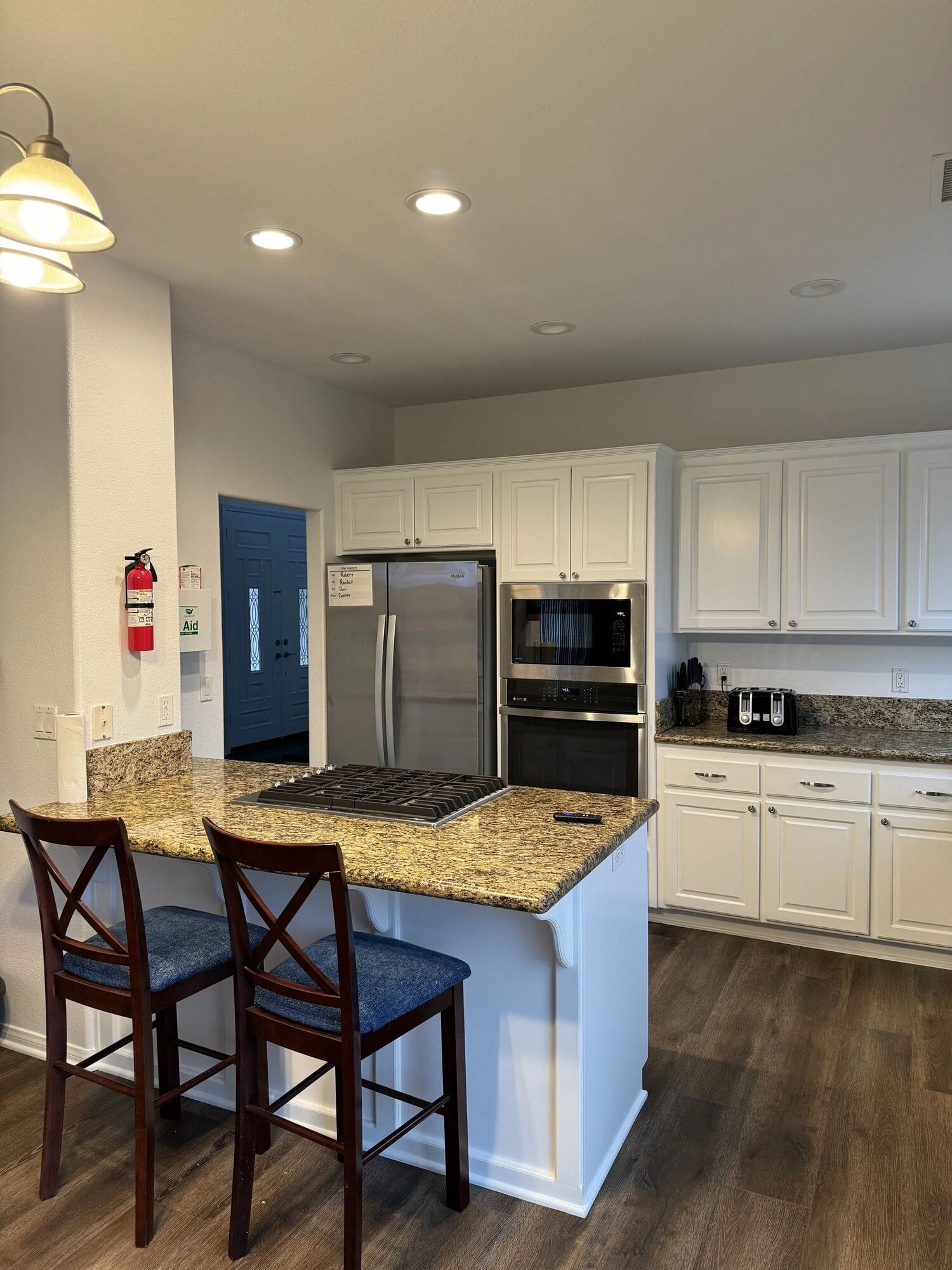 Skyhouse kitchen with white cabinets, granite counters, stainless appliances and bar stools at the island
